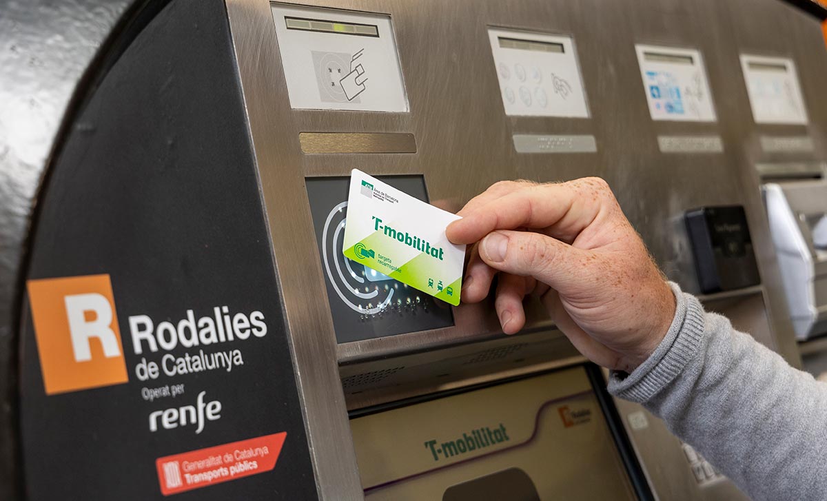 A person is loading a cardboard T-mobilitat card into a machine.