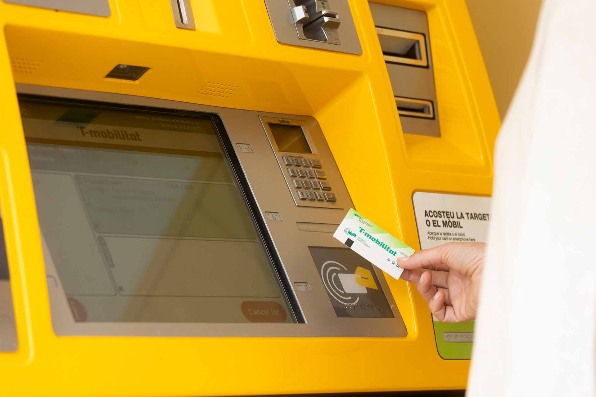 Una persona recarrega una T-mobilitat de cartró en una màquina d'autovenda