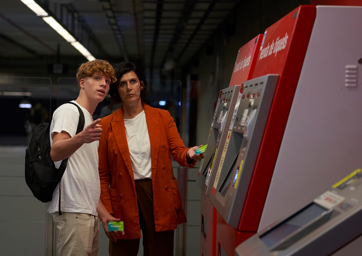 Un fill i la seva mare davant d'una màquina del metro.
