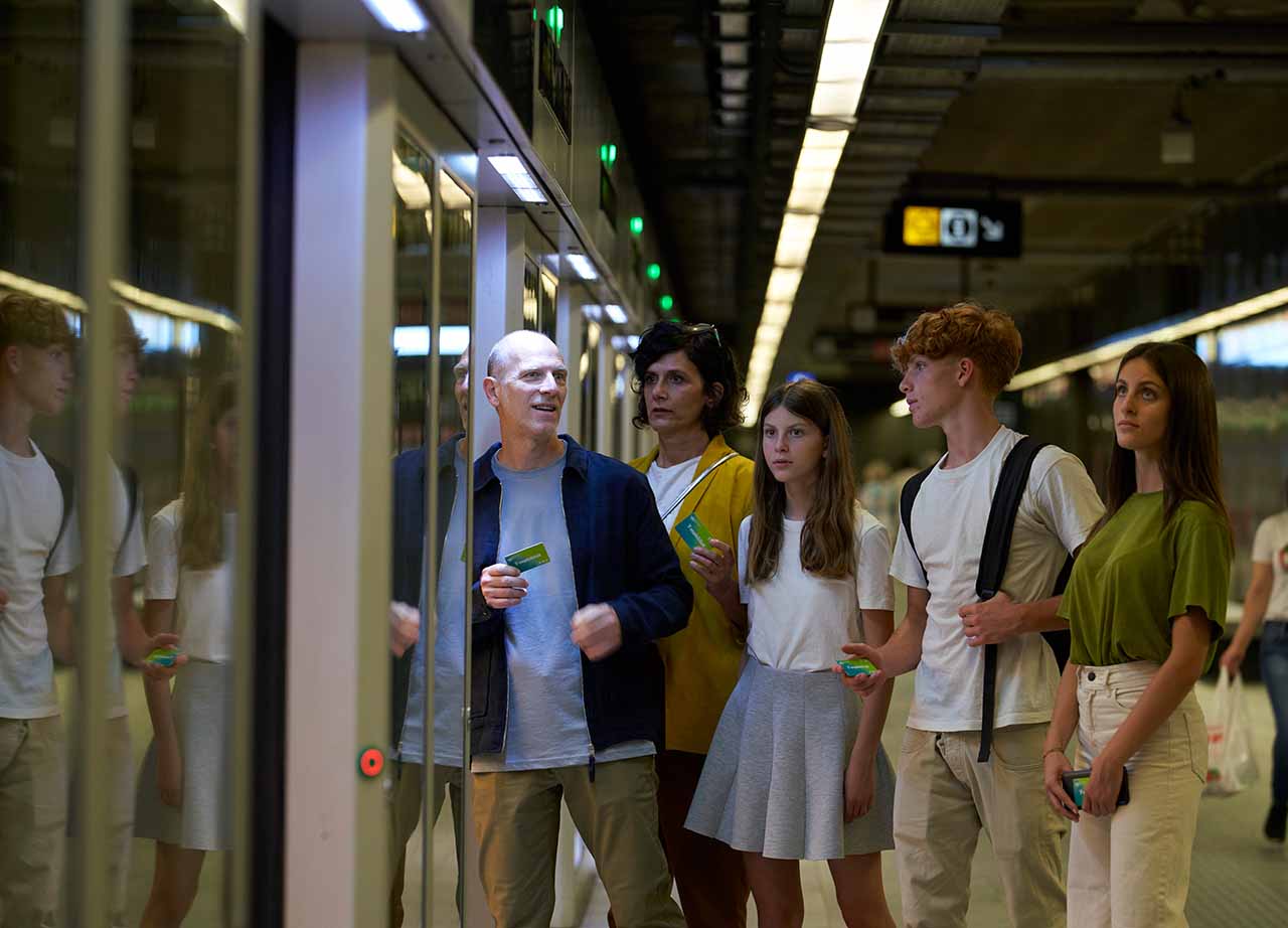 Una familia entra al metro con sus tarjeta T-mobilitat a la mano.
