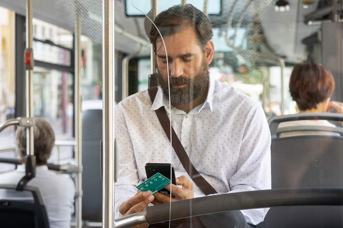 Un home escriu des del seu mòbil en un autobús.