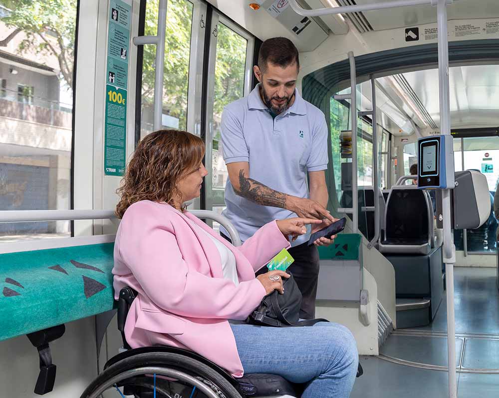 Un agente de TRAM atiende a una usuaria en el tramvia