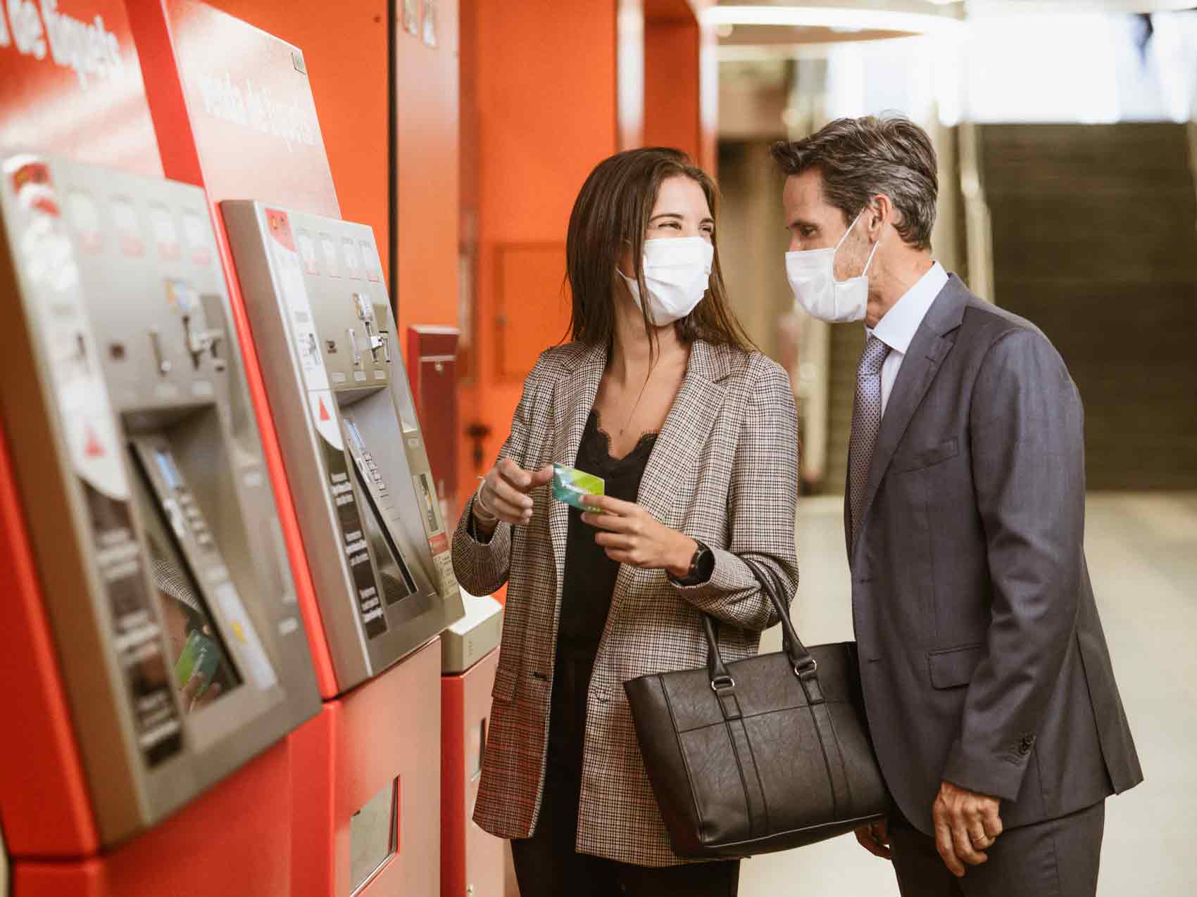Two people recharge the T-mobilitat in a tickets machine.